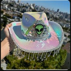 an alien hat is being held up in front of a cityscape with skyscrapers