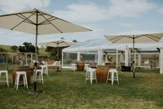 several tables and chairs with umbrellas in the grass