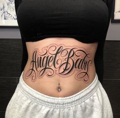 a woman's stomach with the words angel baby written on her lower back tattoo