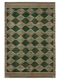 a green and brown rug with fringes on the bottom, in front of a white background