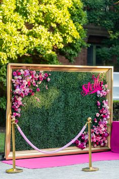 pink and gold wedding decor with flowers on the wall, in front of a green backdrop