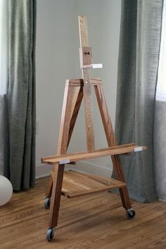 a wooden easel sitting on top of a hard wood floor next to a window