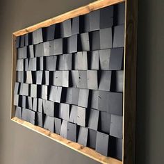 a large wooden frame with many squares on the wall in front of grey walls and flooring