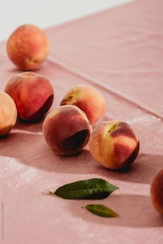 five peaches on a pink cloth with leaves