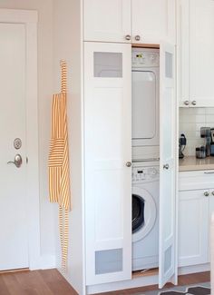 a washer and dryer in a small room with white cabinets on the wall