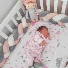 a baby laying in a crib next to a stuffed animal