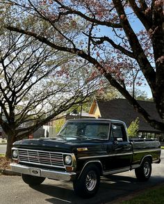 an old pickup truck parked on the side of the road in front of some trees