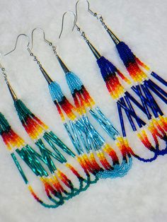 five pairs of earrings with different colors and designs on them, all hanging from hooks