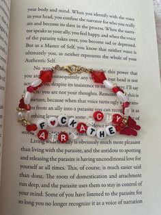 an open book with a bracelet on it that says, love is in the air