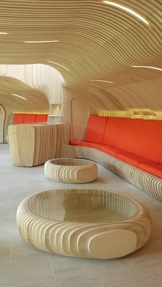 the interior of a modern building with curved wooden walls and orange seats on either side