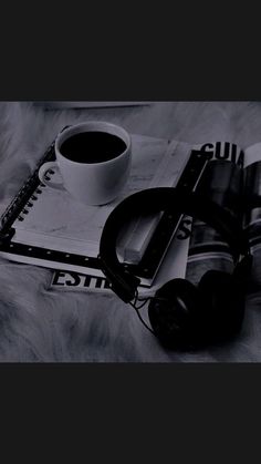 a cup of coffee and headphones on top of a book