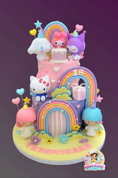 the cake is decorated with hello kitty and rainbows on it's top tier