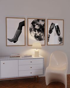 a white chair sitting in front of two pictures on the wall