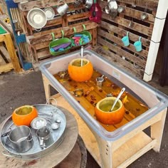 two oranges are sitting in a tray on a table with spoons and pans