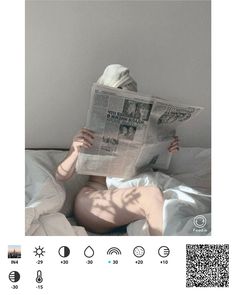 a person laying in bed reading a newspaper