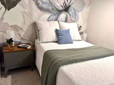 a bedroom with a floral wallpaper and white bedding