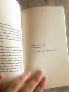 a person holding an open book in their left hand and touching it with both hands