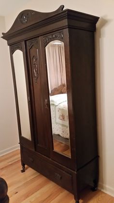 an antique armoire with mirrored doors in the corner and wood flooring on the side