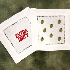 two napkins with embroidered designs on them sitting next to each other in front of a green background