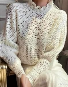 a woman sitting in a chair wearing a white sweater