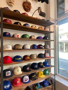 hats are lined up on shelves in front of a window