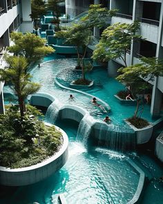 people are swimming in an artificial pool surrounded by trees and water features that resemble waterfalls