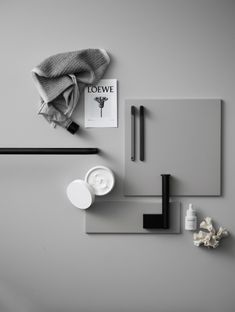 an assortment of items are displayed on a gray surface with black and white accents, such as a towel, scissors, paper clips, and other objects