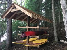 two surfboards are sitting under a shelter in the woods, one is red and one is yellow