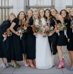 a group of women standing next to each other wearing dresses and holding bouquets in their hands