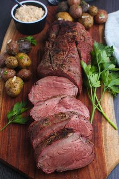 a wooden cutting board topped with meat and vegetables