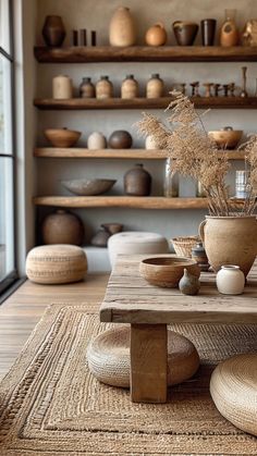 a wooden table sitting on top of a rug next to shelves filled with vases