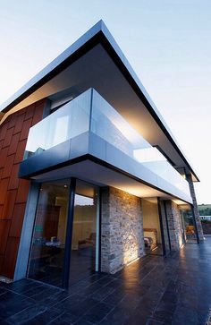 a modern house with large glass windows and stone walls on the outside, overlooking an outdoor patio area