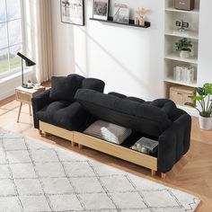 a living room with a black couch and white rug on top of the wooden floor