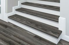 a set of wooden stairs leading up to a white painted room with wood flooring