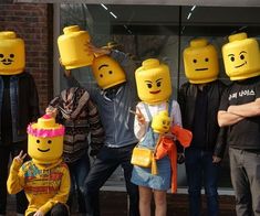 a group of people with legos on their heads standing in front of a building