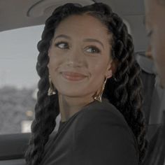 a woman sitting in the back seat of a car with braids on her hair