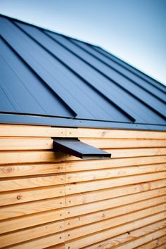 a wooden building with a metal roof and black shingles on the side of it