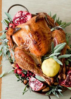 a turkey sitting on top of a platter filled with pomegranates