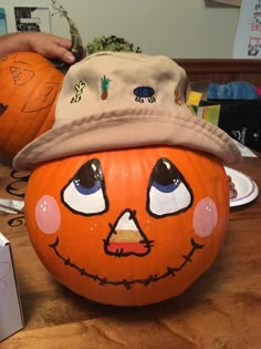 two pumpkins with faces painted on them, one has a hat and the other has eyes