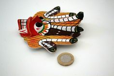 a coin is sitting next to a ceramic figurine that looks like a fish