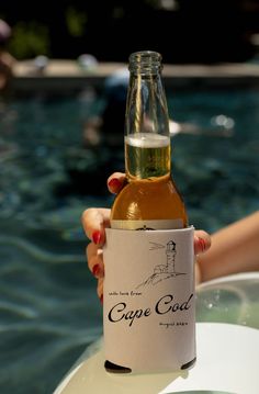 a woman holding up a bottle of wine in front of a swimming pool with the caption cupe god written on it