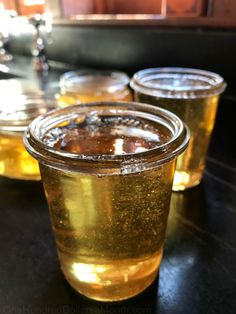 three glasses filled with liquid sitting on top of a black table next to each other