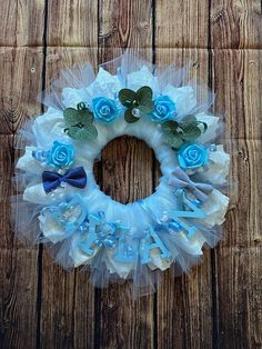 a wreath made out of tulle with blue flowers and bows on it sitting on a wooden surface