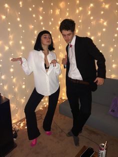 a man and woman dressed up in formal wear posing for the camera with lights behind them