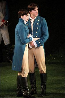 two men dressed in period clothing standing next to each other on the grass at night