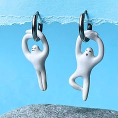 two white figurines hanging from hooks in front of a blue wall with water