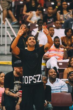 a man standing on top of a basketball court holding his hands up in the air