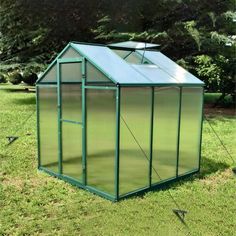 a small green house sitting on top of a lush green field