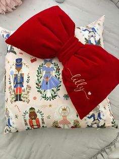 a pillow with a red bow on it sitting on top of a bed next to other pillows