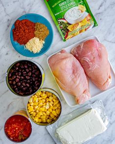 ingredients to make mexican chicken recipe laid out on a marble counter top, including black beans, corn, tomatoes, and cheese